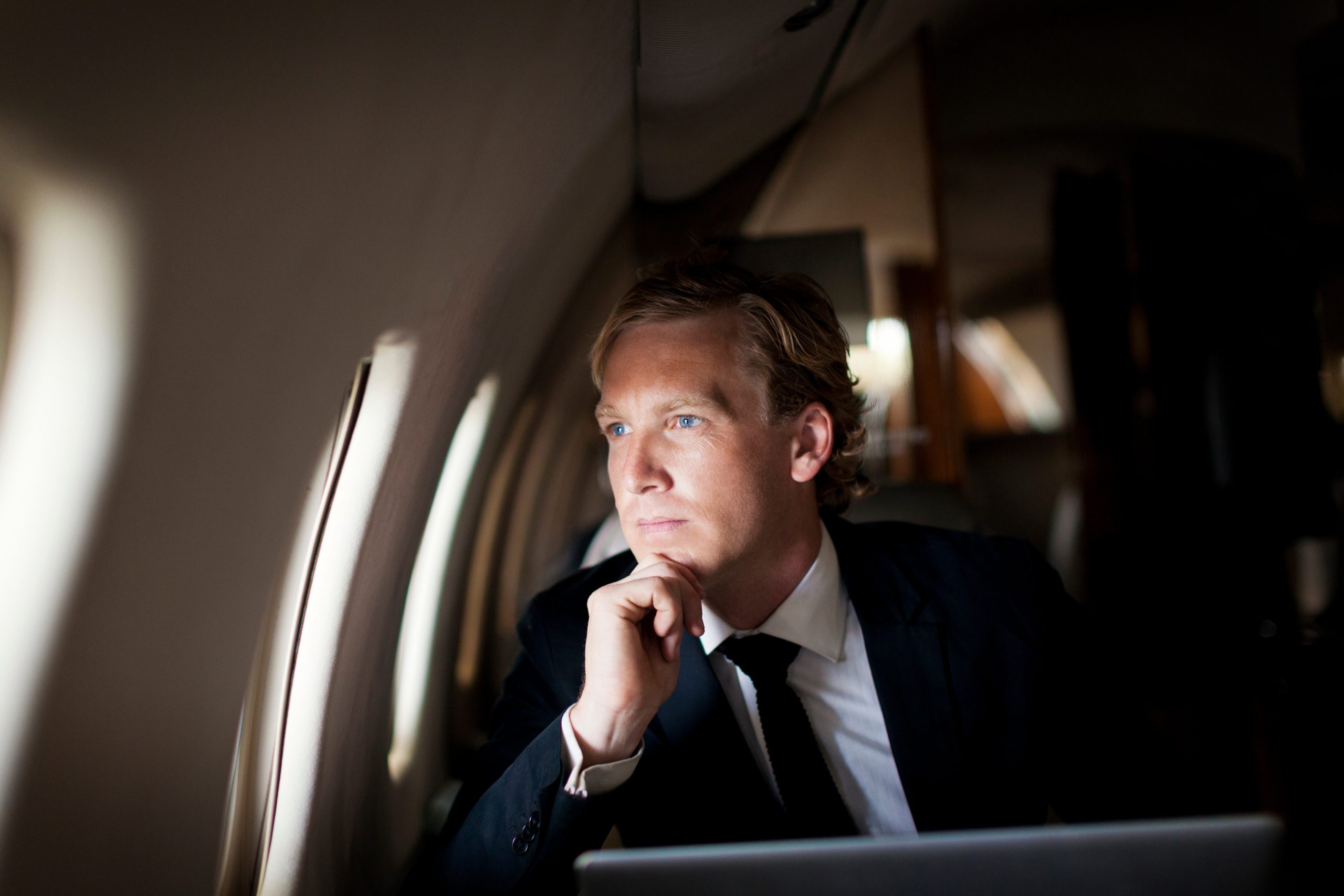 Businessman looking through window while sitting in airplane